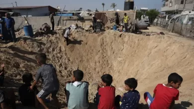 Palestinian children sit at the edge of a crater after an Israeli air strike in Khan Younis, southern Gaza Strip [File: Jehad Alshrafi/AP]