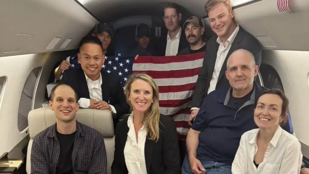 This image released by the White House shows Evan Gershkovich, left, Alsu Kurmasheva, right, and Paul Whelan, second from right, and others onboard a plane after their release from Russian captivity