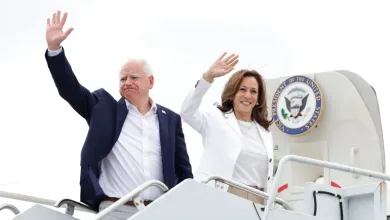 Tim Walz and Kamala Harris waving on a campaign tour