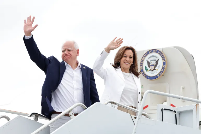 Tim Walz and Kamala Harris waving on a campaign tour