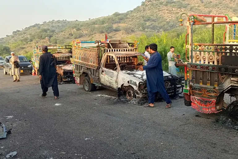 People look at burned-out vehicles