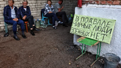 residents of Ukrainian -controlled Russian town of Sudzha sitting next to a sign reading;there are civilians in the basement