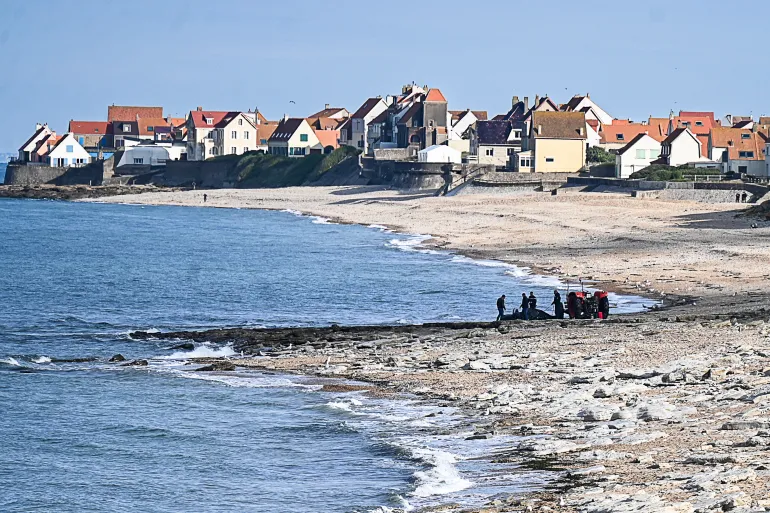 French gendarmes use a tractor to pull a damaged boat used by asylum seekers after a failed attempt