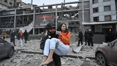 A Ukrainian police officer evacuates a woman from a building destroyed by a Russian missile strike in Zaporizhzhia