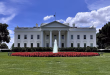 A contemporary colour view of the White House’s north façade in Washington, DC, showing its white neoclassical portico, columns, North Lawn fountain and landscaped grounds.