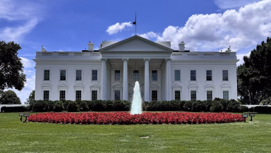 A contemporary colour view of the White House’s north façade in Washington, DC, showing its white neoclassical portico, columns, North Lawn fountain and landscaped grounds.