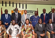 A group of formally dressed people pose for a photograph indoors in front of a Minerals Income Investment Fund sign.