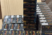 Stacks of black boxed products are arranged on a table or counter indoors.