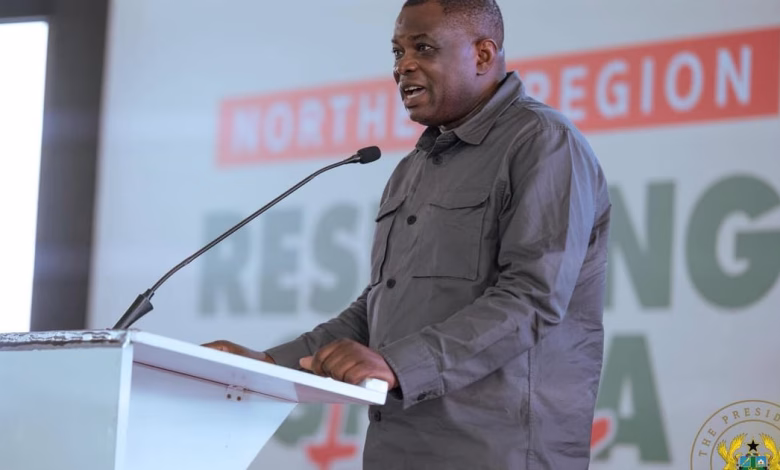 A man speaks at a lectern with a microphone in front of a presentation backdrop.