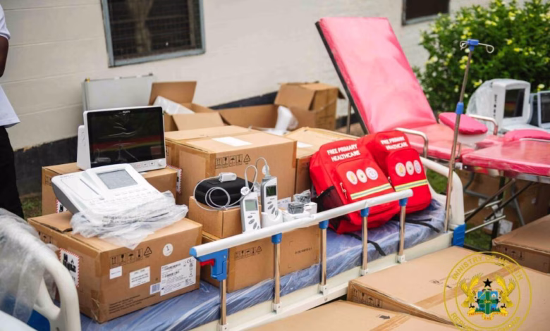 Medical equipment, hospital beds, boxed supplies, and emergency bags are arranged outside a building.