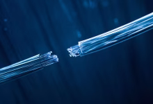 A close-up illustration shows two severed bundles of glowing blue fiber-optic cables separated against a dark blue background.