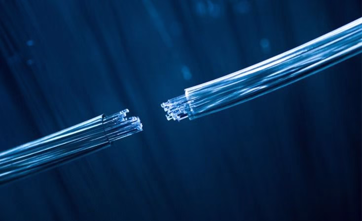 A close-up illustration shows two severed bundles of glowing blue fiber-optic cables separated against a dark blue background.