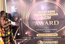 Several people stand beside a large event display for the Ghana Journalists Association Western Region Media and CSI Award.